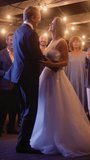 Vertical Screen: Beautiful Bride in White Dress and Groom in Stylish Black Suit Celebrate Wedding at an Evening Reception Party. Newlyweds Dancing at a Venue with Best Multiethnic Diverse Friends.