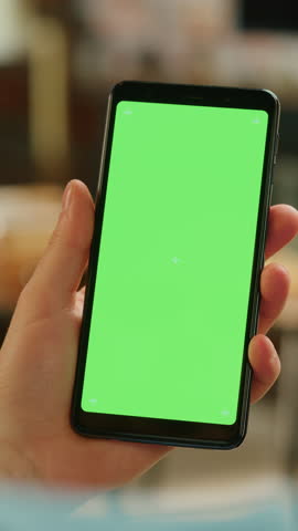 Vertical Screen: Hand Scrolling Feed on Smartphone with Green Screen Mock Up Display. Person Resting at Home and Checking Social Media on Mobile Device. Close Up Over the Shoulder Footage. Royalty-Free Stock Footage #3452164253