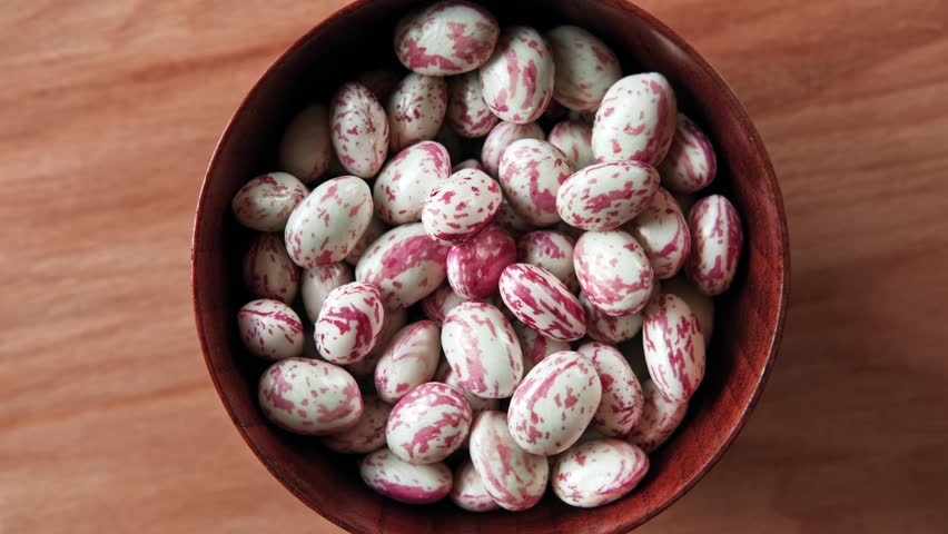 Cranberry beans spinning. Borlotti bean pods in wooden bowl. Top view. Stylish modern food background. Magenta color. Creative foodstuff flat lay. Grocery, dietary backdrop. Advertising, trendy video Royalty-Free Stock Footage #3452184781