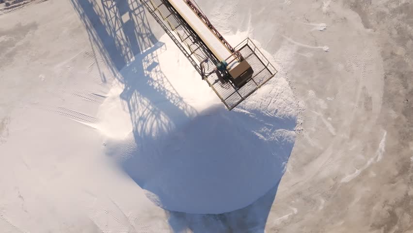huge pile of salt conveyor belt moving sea salt produced by the evaporation of seawater.piles of white mineral salt and industrial equipment in a salt factory. Royalty-Free Stock Footage #3452196027