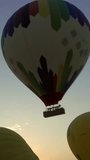 Hot-air balloons starting flying at sunrise, timelapse. Vertical video