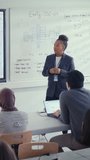 Black Teacher Tell to Students and Point at Whiteboard at University Lecture Class. Diverse Group of Young Developers Listen at Seminar. Education Concept. Vertical View