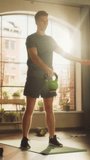 Vertical Screen: Athletic Fit Man Swinging a Heavy Kettlebell from Hand to Hand, Doing Core Strengthening Exercises During Morning Workout at Home in Sunny Apartment. Concept of Health and Fitness.