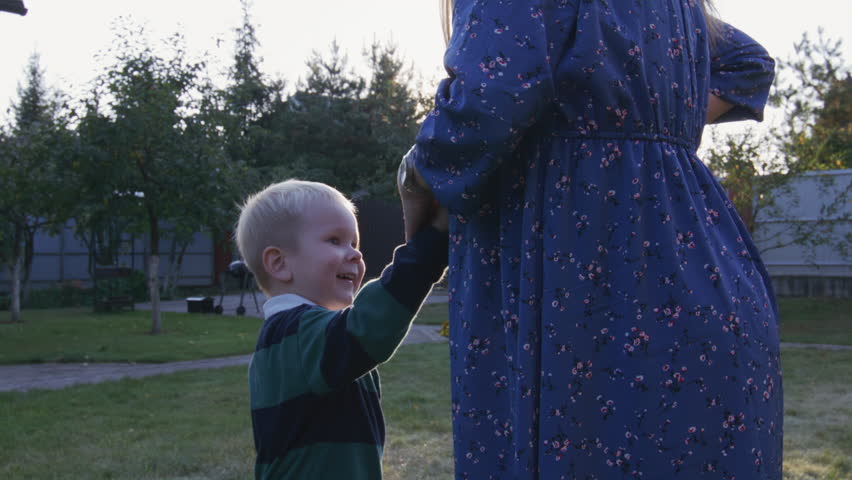 Little boy rubbing his pregnant mom's belly outdoor 