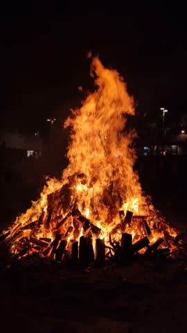 View of a large bonfire lit at night as part of popular and ancestral celebrations in the squares of villages and cities from the Mediterranean. Vertical format Royalty-Free Stock Footage #3452271081