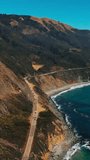 Cars going quickly by the dangerous highway on the rocks of California. Great scenery of beautiful mountains watered by Pacific Ocean waters. Vertical video.