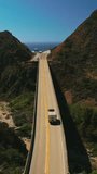 Following the truck riding by the dangerous mountainous highway of California on sunny day. Amazing blue ocean opening to the view. Vertical video.