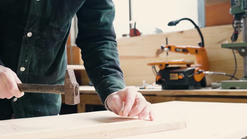Man tinkering in his workshop, hitting a nail with a hammer Royalty-Free Stock Footage #3452345083