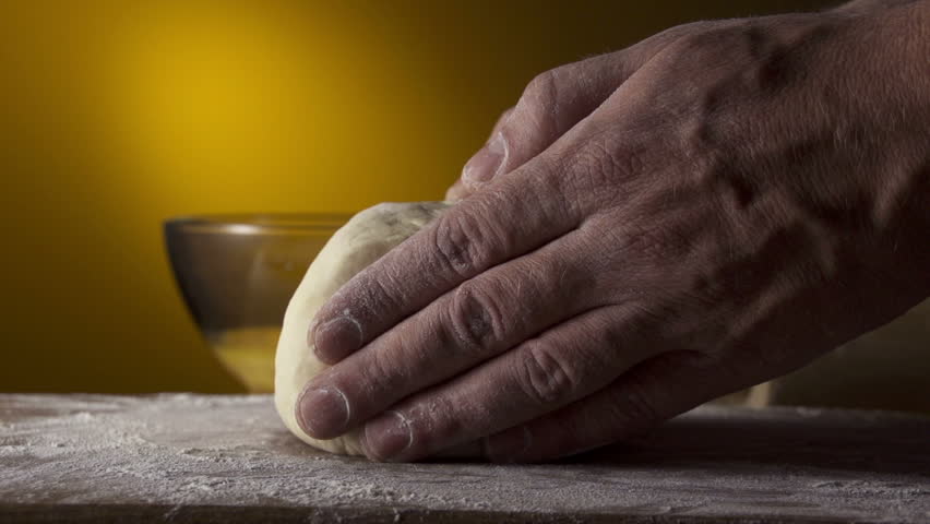hands in flour closeup kneading dough on table slow motion