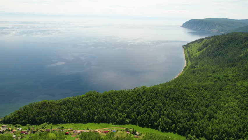 Picturesque summer landscape. The shore of Lake Baikal on a sunny day, mountains covered with forest
