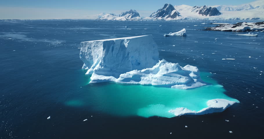 Antarctica melting iceberg float blue water polar ocean. Arctic Ice natural beauty of towering glacier, blue sunny sky. Ecology, melting ice, climate change, global warming. Aerial drone panorama