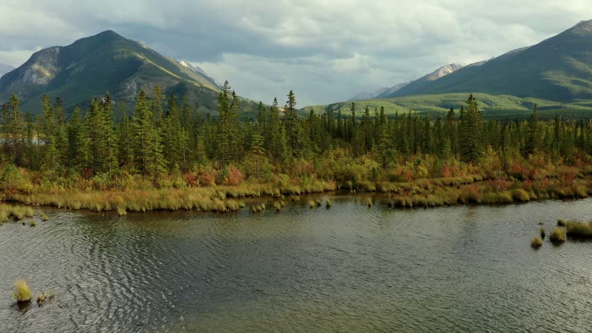 Beautiful aerial view of the Vermilion Lakes and Sulphur Mountain full of pine trees, in autumn on a cloudy day near Banff, Canada. Royalty-Free Stock Footage #3452430261