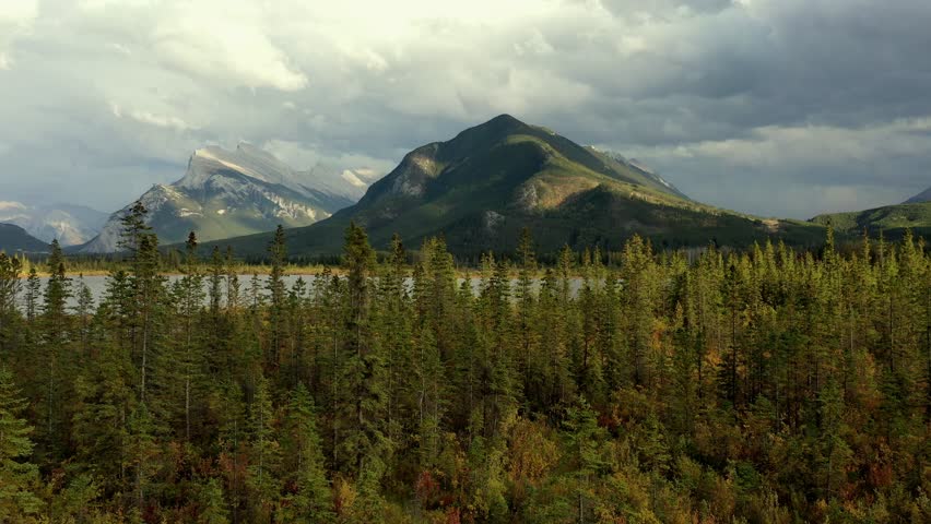 Beautiful aerial view of the Vermilion Lakes and Sulphur Mountain full of pine trees, in autumn on a cloudy day near Banff, Canada. Royalty-Free Stock Footage #3452430787