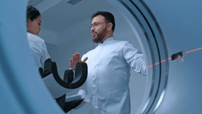 Diagnostic room at hospital, radiologist monitors MRI, CT or PET scan of patient undergoing procedure. Professional doctor performs emergency examination procedure using advanced medical technologies - Powered by Shutterstock - Get 15% off with code: PIKWIZARD15