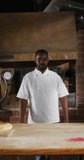 Vertical video of portrait of african american male baker in bakery. global business and bakery.