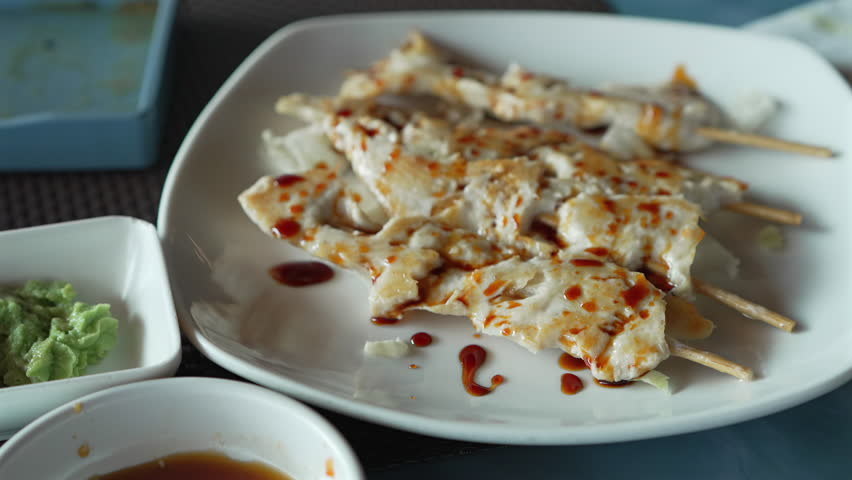 Teriyaki chicken skewers on plate at restaurant, slow motion shot at 30 fps