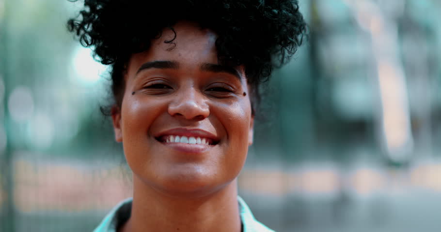 Close-up of one young black latina woman smiling at camera in tracking shot. Friendly expression of 20s person of African descent portrait
