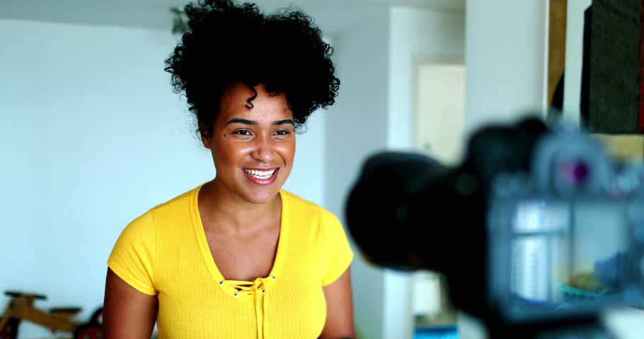One young black woman speaking in front of camera giving testimony for online channel. 20s female vlogger creating video post engaged with new media