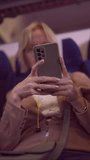 VERTICAL VIDEO, Close-up of a mature woman's hands using a smartphone while traveling by train. Soft focus, slow motion