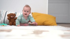 Cute baby newborn smile and  lies on his stomach, trying to hold his head and learns to crawl on a play mat for outdoor activities at home.  4k format video.