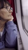 VERTICAL VIDEO, Close-up of elderly woman in glasses travels by train looking out the window