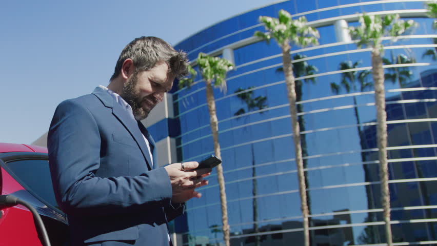 Zoom out CEO executive businessman using smartphone at modern office building. Mature concentrated businessman in blazer looking at mobile phone. Collage of diverse people working together remotely 4K Royalty-Free Stock Footage #3452535449
