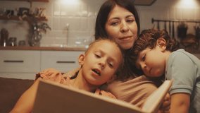Mother enjoys reading storybook with her daughter and son, cuddling together on couch in cozy home setting, enjoying warm family moment - Powered by Shutterstock - Get 15% off with code: PIKWIZARD15