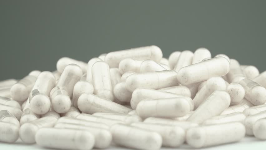 The slow spin of white capsules with vitamins and nutritional supplements helps maintain health. The beauty and benefits of vitamins from capsules: ease of use. Pharmaceuticals