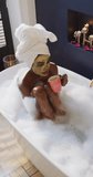 Vertical video of african american woman drinking coffee, pampering herself in foam bath. domestic lifestyle, enjoying leisure spa time at home.