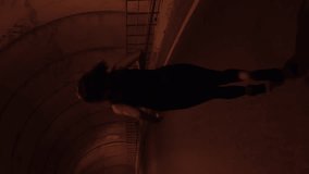 Woman running along tunnel, back follow shot. Female athlete running fast through tunnel. Outdoor jogging training. Vertical video