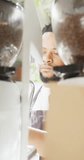 Vertical video of african american male barista preparing coffee in cafe. global business and barista cafe.