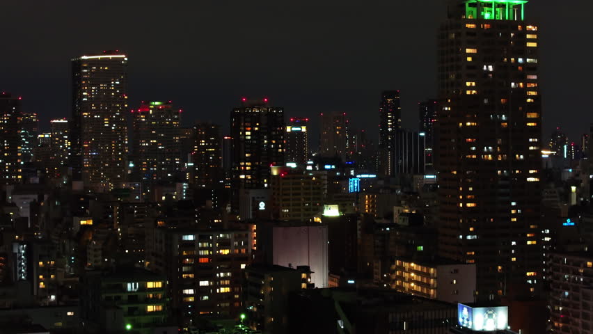 Aerial ascending footage of modern high rise apartment buildings in residential urban district. Night city scene. Osaka, Japan