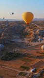 Vertical Aerial video. Captured against the canvas of the Cappadocian sky, this video showcases the enchanting spectacle of a hot air balloon festival. The vibrant balloons rise gracefully over the