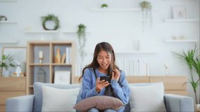 Happy young asian woman relax on comfortable couch at home texting messaging on smartphone, smiling girl use cellphone, chatting online message, shopping online from home - Powered by Shutterstock - Get 15% off with code: PIKWIZARD15