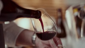 A close-up of red wine being poured from a bottle into a wine glass, the wine flowing smoothly into the glass, creating a slight splash as it fills up - Powered by Shutterstock - Get 15% off with code: PIKWIZARD15