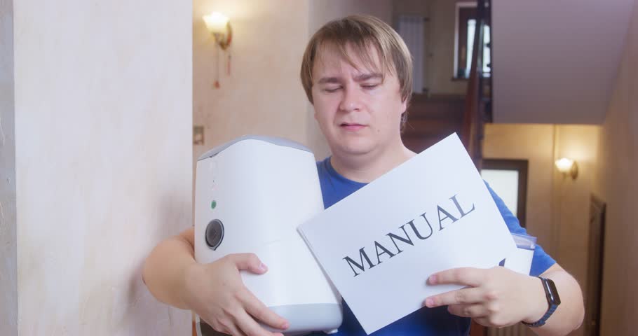 A man looks confused while holding a large manual and a white device, representing the universal struggle with new technology. The focus on the manual underscores his search for understanding.