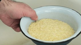 Man Pouring Water into Rice Bowl for Pre-Cooking Rinse, Static Shot