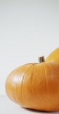 Vertical video of two large pumpkins rotating on white background. seasonal organic vegetables and healthy foods.