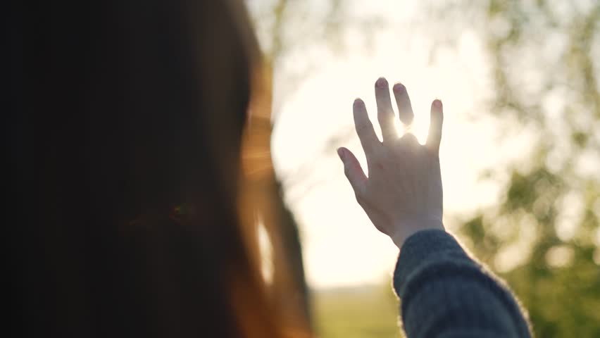 Hand of happy girl at sunset. Sunset between the hands of girl. Happy girl with long hair dreamily stretches out her hand to sun. Child's dream hand to the sun. happy family concept. Freedom in nature Royalty-Free Stock Footage #3452825479
