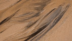 Sand and water texture. 4K close up video with the abstract shapes created by a tiny water river over the sands at Atlantic Ocean shore.