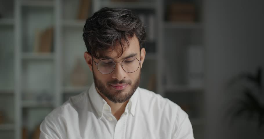 Portrait of handsome manager sitting at office, wearing shirt and eyeglasses.
