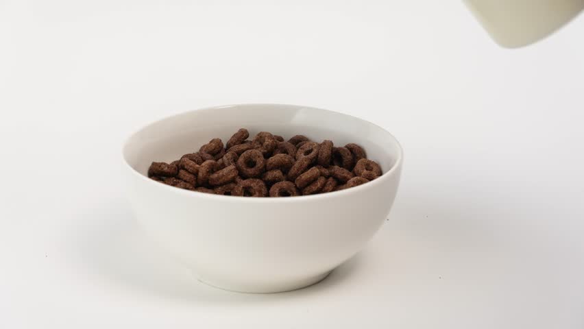 Cereals and milk. Milk being poured on flakes. Chocolate rings on white background. Healthy nutrition and people concept. breakfast cereals. Healthy food. Cereals in white bowl.   Royalty-Free Stock Footage #3453035971