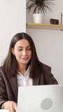 Vertical video footage of two professional entrepreneur partners celebrating business success in light office. Successful young man and woman achieving goals at co-working workspace. Teamwork concept
