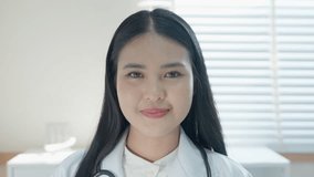 Close up of confident young asia female doctor talk on video call consult in white medical uniform and smiling at hospital, video conference call. medical nurse in Webcam conference with coworkers
