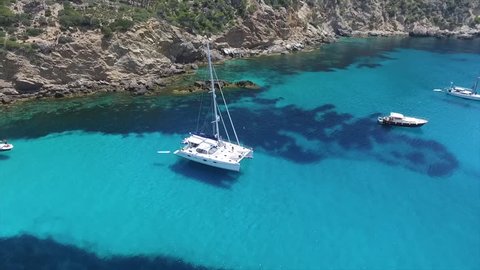 Summer Chilling Fun vibes! Beautiful drone video of a sail boat anchored in a turquoise cove. This Catamaran super yacht is the perfect place to relax! 1080p 60fps.