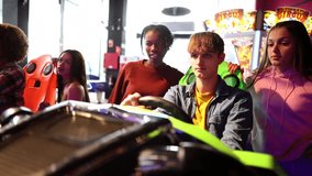 group of young people playing car racing simulator in the arcade room