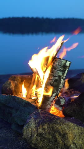 A bonfire burning in a forest on the shore of a lake at midnight on the Summer Solstice. Summer White Night on the eve of Midsummer Day in Finland. Sound of campfire and wildlife, birdsong Royalty-Free Stock Footage #3453330629