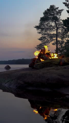 A bonfire burning in a forest on the shore of a lake at midnight on the Summer Solstice. Summer White Night on the eve of Midsummer Day in Finland. Sound of campfire and wildlife, birdsong Royalty-Free Stock Footage #3453336457