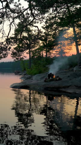 A bonfire burning in a forest on the shore of a lake at midnight on the Summer Solstice. Summer White Night on the eve of Midsummer Day in Finland. Sound of campfire and wildlife, birdsong Royalty-Free Stock Footage #3453346615
