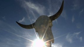 Time Lapse, Sun star shines through cracks in horned, cow skull as clouds glide by in blue sky. 1080p - Powered by Shutterstock - Get 15% off with code: PIKWIZARD15